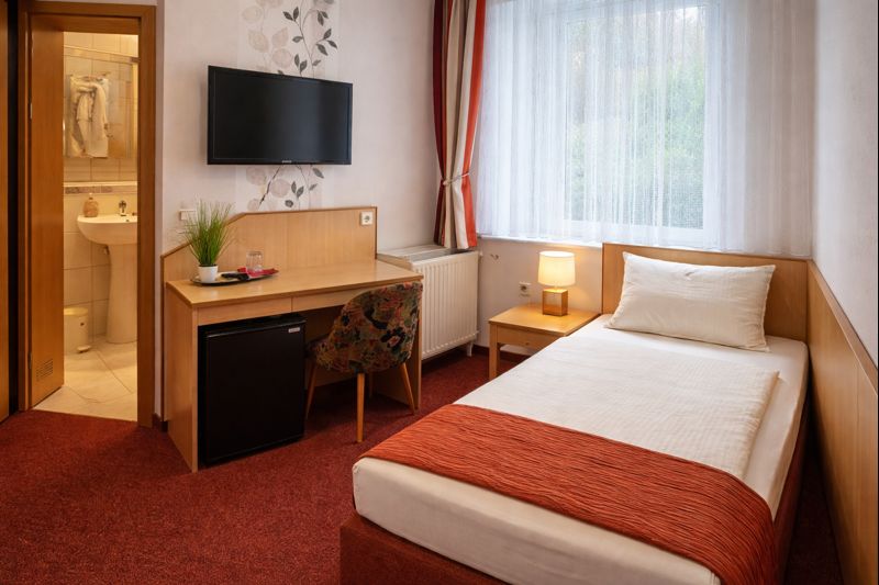 Einzelzimmer mit Bett und Schreibtisch